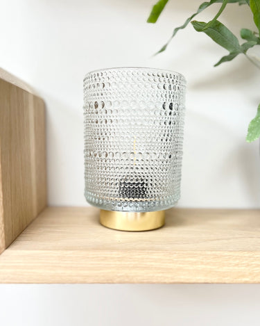 Battery operated lamp with etched design on glass and gold bottom in lifestyle photo